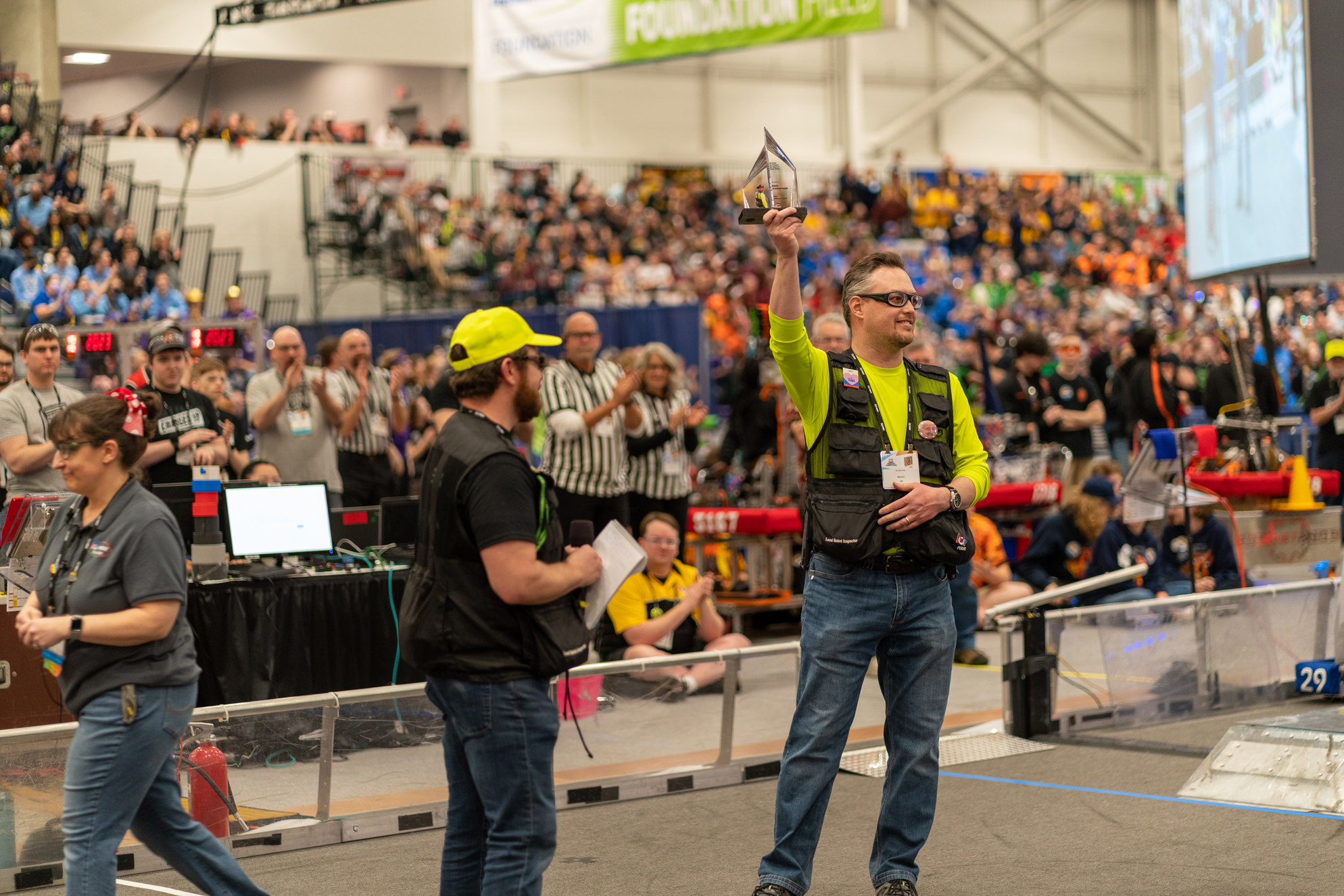 Man holding aloft a glass award while another man looks on